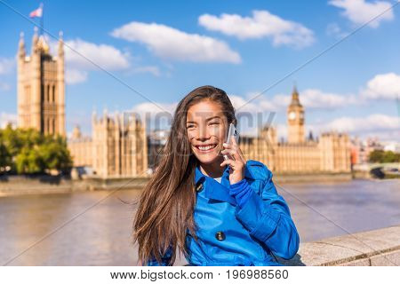 London city businesswoman calling on mobile phone app talking to cellphone at Westminster Houses of Parliament background. Asian tourist woman Europe travel destination, England, Great Britain.