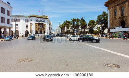 Rabat Morocco - May 06 2017: Cars are driving on the Central Square in Rabat Morocco past the French colonial telegraph and post office building while people are walking about. Motion blur.