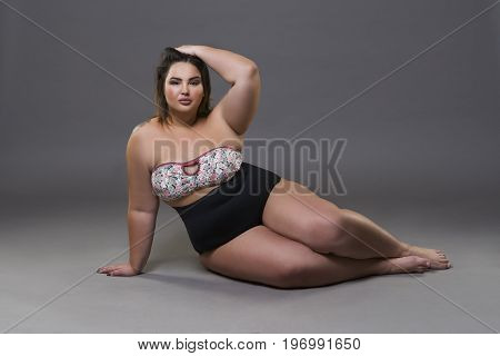 Plus size fashion model in sexy swimsuit young fat woman on gray studio background overweight female body full length portrait