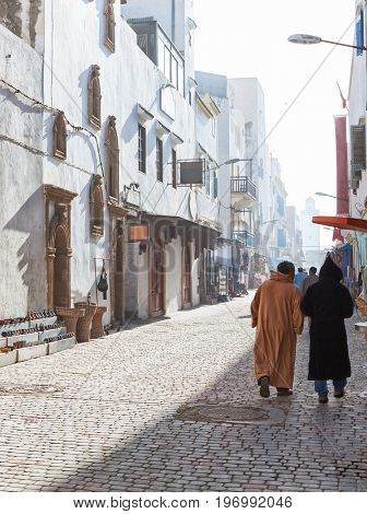 Unhurried  city life in misty  sunny  morning   on  shopping street ,  medina of Essaouira, Morocco.