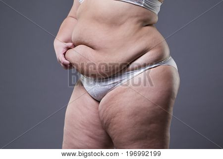 Woman with fat abdomen overweight female stomach on gray studio background