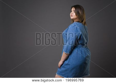 Plus size fashion model in casual jeans clothes fat woman on gray studio background overweight female body full length portrait