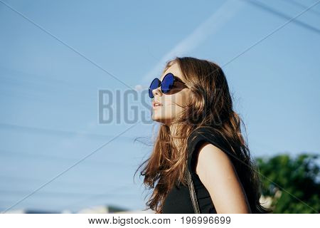 Young beautiful woman in sunglasses walking along a street in a city in the fresh air.