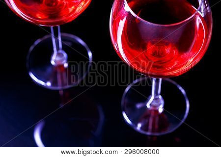 Two Glasses Of Red Wine In Night Club On Black Background With Reflection.