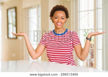 Young beautiful african american woman at home Smiling showing both hands open palms, presenting and advertising comparison and balance