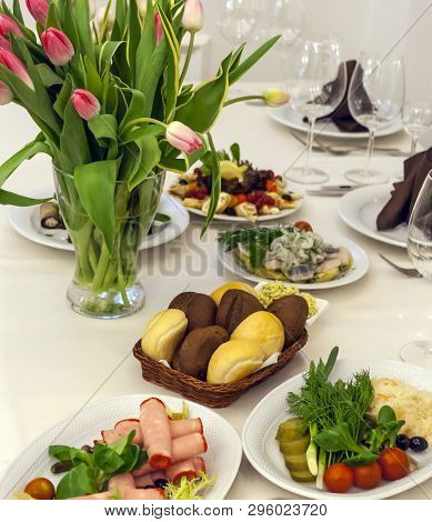 Bouquet Of Tulips, Plates With Snacks And A Basket Of Bread On A Festive Table Covered With A White 