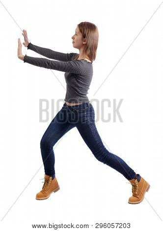 back view of woman pushes wall.  Isolated over white background. Rear view people collection. backside view of person. Girl in jeans and boots pushing the wall in front of her.