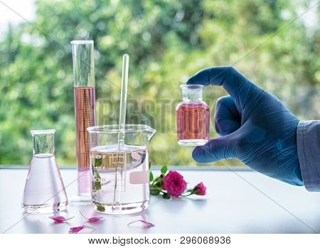 The Humand Hand Wearing Blue Rubber Glove Holding The Nature Organic Extract Bottle ,aromatic Essent