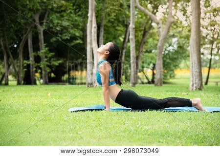 Theb Eauty Woman Wearing Exercise Suit,stretching Body On Yoga Matt,posing Yoga Pattern,in A Park,mo