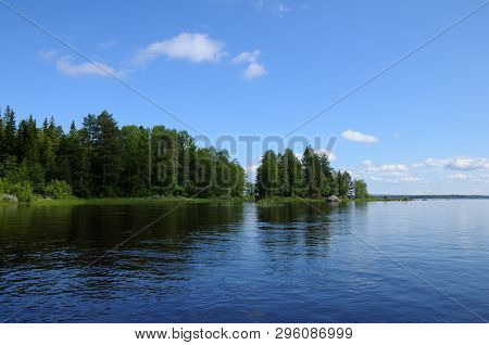 The Beautiful Picture Of Karelian Forest At The Edge Of A Lake, And Some Huge Boulder In This Lake