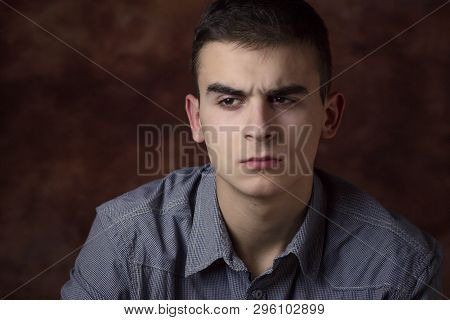Closeup Portrait Of Young Man With Brown Background. Very Serious Face Expression, Suspicious. Human