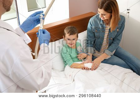 Doctor Adjusting Intravenous Drip For Little Child In Hospital During Parent's Visit