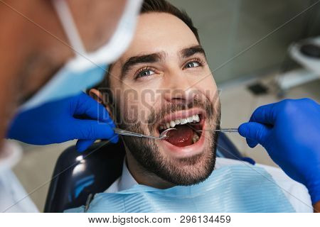 Image of a handsome happy young man sitting in medical dentist center.