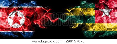 North Korea Vs Togo, Togolese Smoky Mystic Flags Placed Side By Side. Thick Colored Silky Smoke Flag