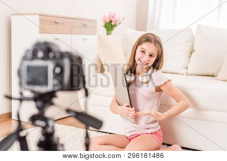 Young smiling videobloger teen girl is pointing at camera in living room
