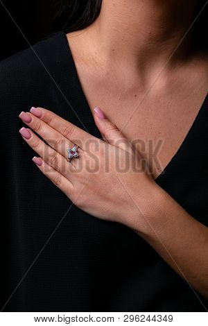 Womens Silver Ring In The Shape Of A Flower With Red Stone In The Middle On Finger, On A Black Backg