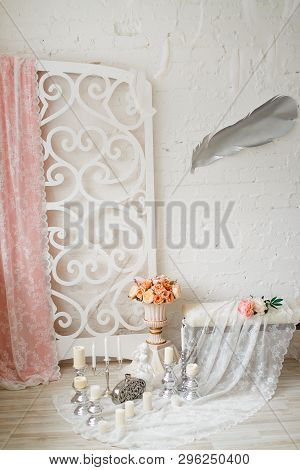 Against The Background Of A White Brick Wall And A Carved Screen With A Pink Curtain And Lace, Stand