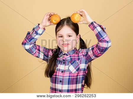 Enjoying Her Favorite Muffin Flavor. Happy Little Girl Holding Breakfast Muffins At Head. Small Chil
