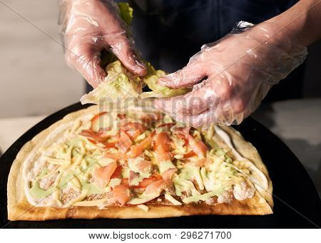 Chefs Cropped Hands In Disposable Gloves Tearing Green Leaves Of Lettuce On Round Thin Baked Base Fo