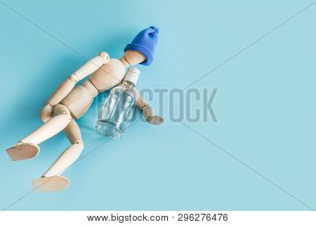 Wooden Doll With Bottle Of Vodka On Blue. Concept Harm Of Alcohol, Drunkenness, Alcoholism. Space Fo