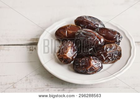 Dried Dates In A White Small Plate On Wooden Table. Traditional Sweet Food In The Middle East