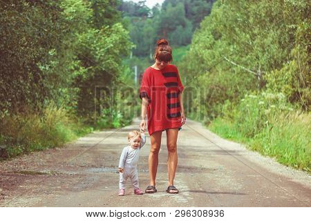 The Child Learns To Walk In The Park Barefoot On The Grass