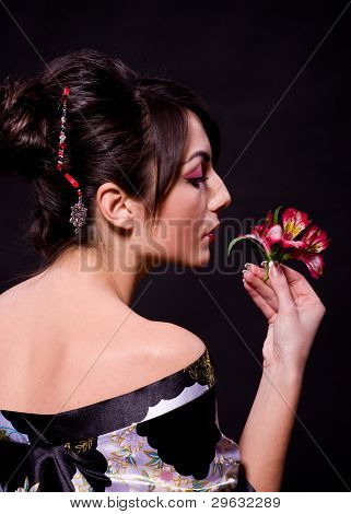 Beautiful young woman in Asian costume with red flowers