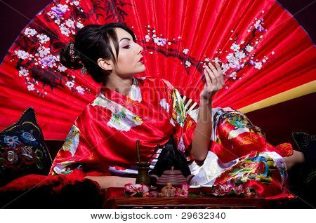 Woman in red Asian costume arranging Japanese tea ceremony