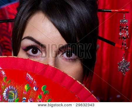 Beautiful young woman in Asian costume with red Asian fan