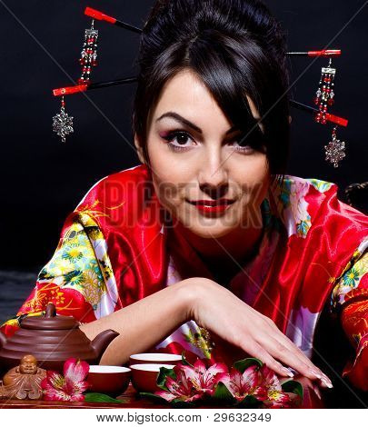 Woman in red Asian costume arranging Japanese tea ceremony