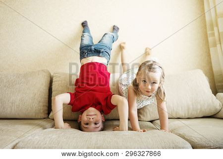 Brother And Sister Playing On The Couch: The Boy Stands Upside Down.