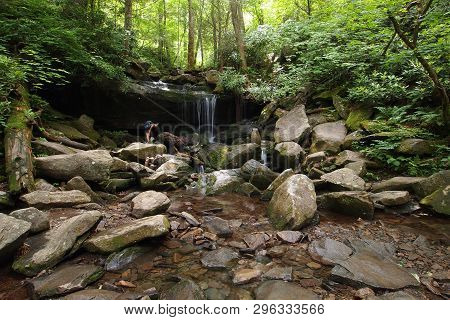 Young Woman Explores A Small Trailside Waterfall In The Great Smoky Mountains National Park, Tenness