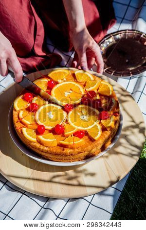 Female Cut Pie With Oranges For A Event Day On Picnic Chacked Cloth. Side View