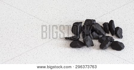 Shungite Stones On White Background With Copy Space.