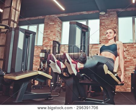 Young Woman Exercising With The Leg Extension Machine At Gym