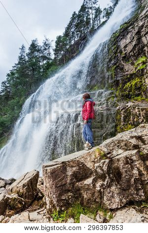 Tourist Woman At Svandalsfossen In Norway, Powerful Waterfall In Norwegian Mountains. National Touri