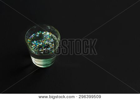 Microplastic In A Glass Of Water On Black Background. Water Pollution. Microplastic Problem. Threat 