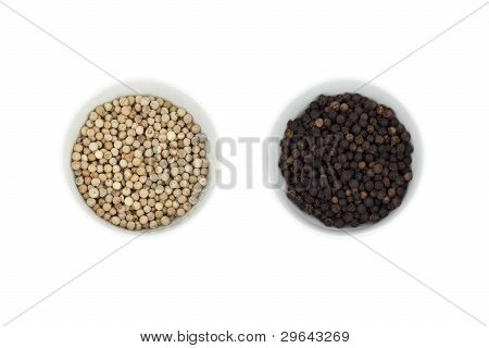 Zwarte en witte peper in een klein kopje geïsoleerd op wit.