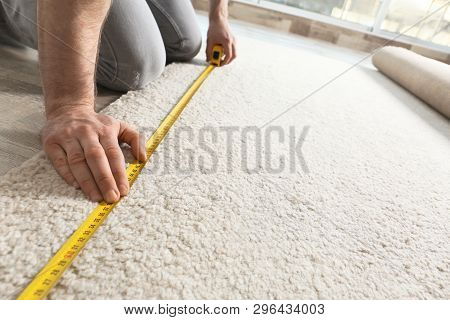 Man Measuring Carpet Indoors, Closeup View. Construction Tool