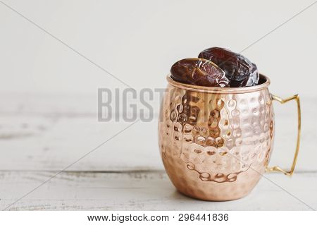 Big Brass Mug With Sweet Dried Dates On Wooden Table, Copy Space