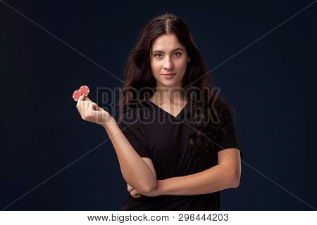 Curly Hair Brunette Is Posing With Red Gambling Chips In Her Hands. Poker Concept On A Black Backgro