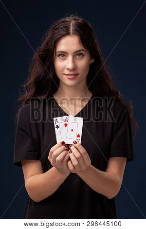 Close-up Shot Of Curly Hair Brunette Posing With Playing Cards In Her Hands. Poker Concept On A Blac