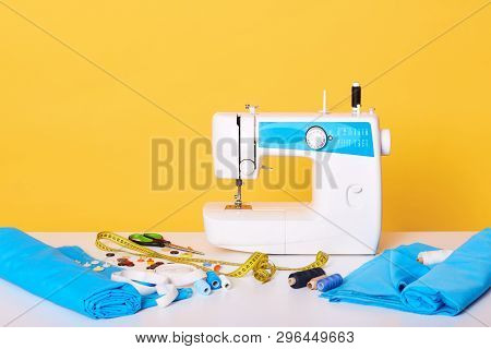 Studio Shot Of Sewing Equipments, Sewing Machine, Tap Measure, Scissors, Pieces Of Cloth, Needles, T