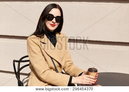Smiling Fashionable Businesswoman With Bright Red Lips Sitting In Bright Wooden Chair, Holding Paper