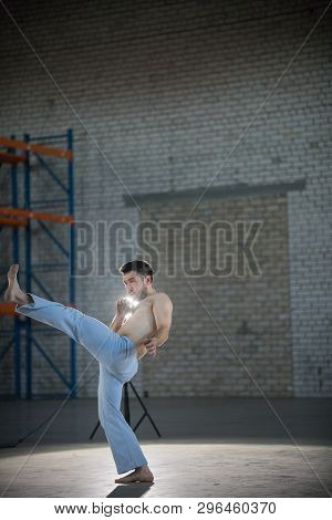 An Athletic Man On Capoeira Training. Performs The Kick