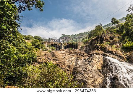 Railway Bridge Over The River Mandovi On The Background Of The Dudhsagar Waterfall