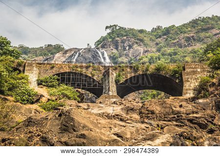 Railway Bridge Over The River Mandovi On The Background Of The Dudhsagar Waterfall