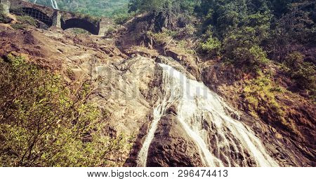 Railway Bridge Over The River Mandovi On The Background Of The Dudhsagar Waterfall