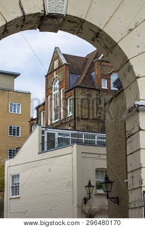 Brick Multi-level House With Large Beautiful Windows. Picture Taken Through The Old Arch. Central Lo