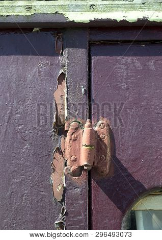 Old Railway Carriage With Close-up Of Door Hinge Showing Distressed Peeling Red Paint And Old Screw 